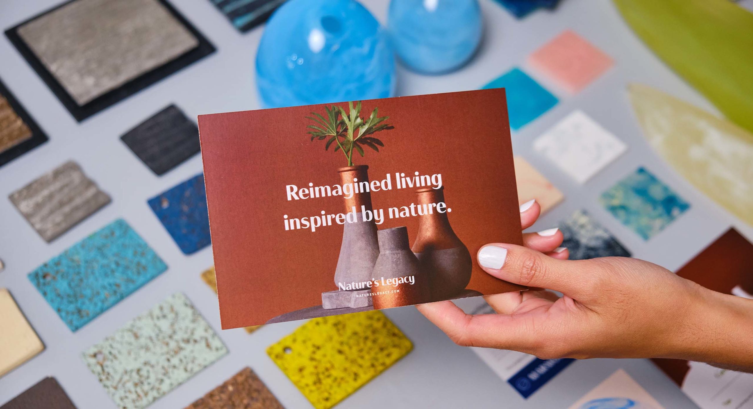 A hand holding a postcard for home and furniture brand Nature's Legacy