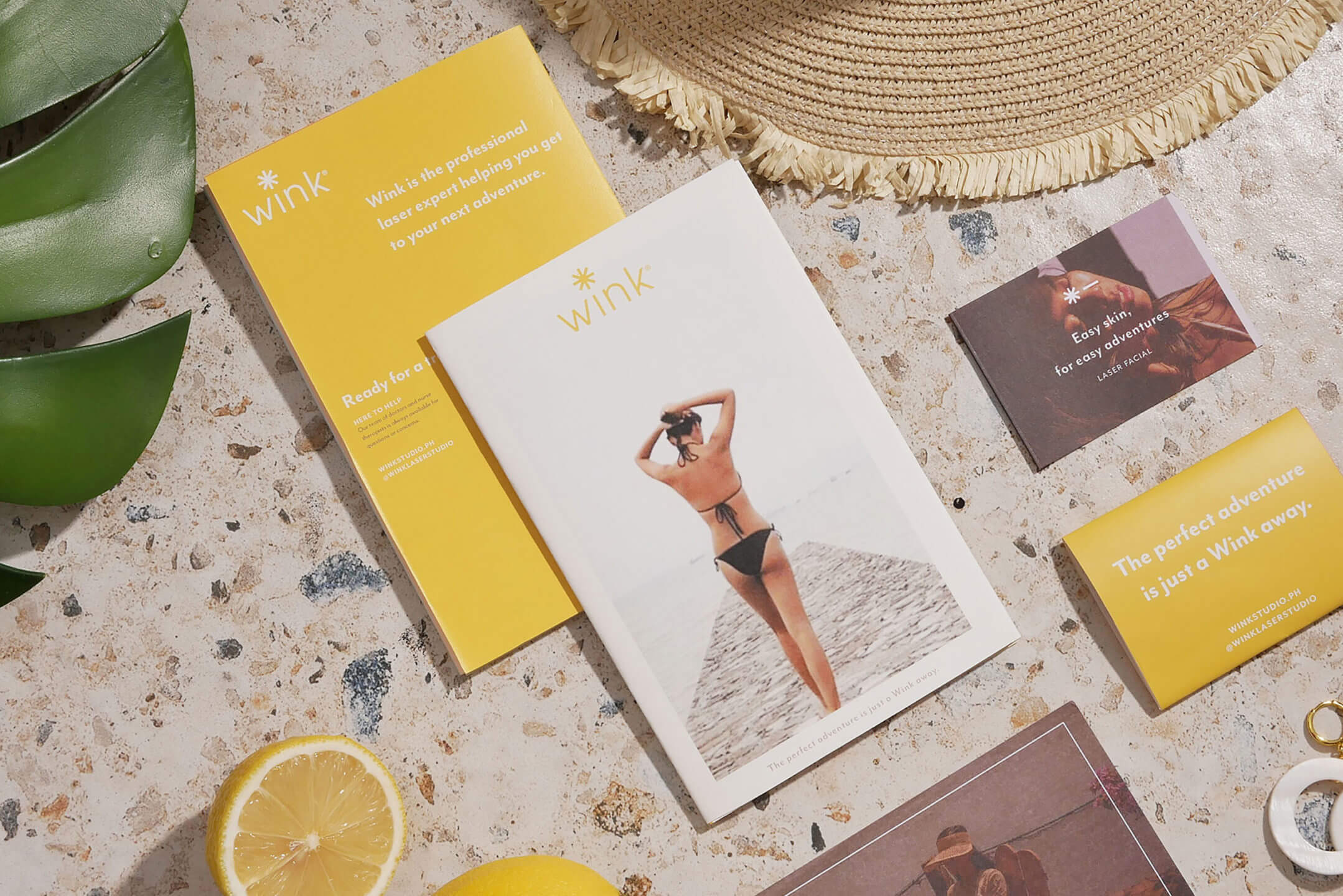 A flat lay of brand collaterals and brochure design for beauty service brand Wink Laser Studio